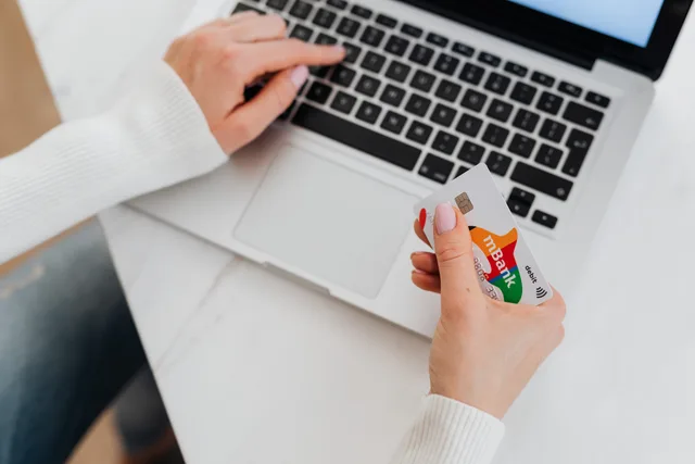 Close-up of a person using a laptop and holding a credit card for online shopping. Hvilke betalingsløsninger findes til danske webshops?