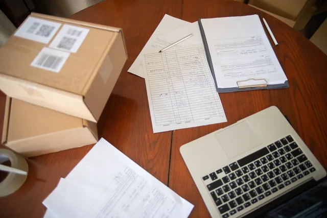 Flat lay of a workspace with laptop, documents, and cardboard boxes for e-commerce operations. Bogføringsloven for små virksomheder: En introduktion