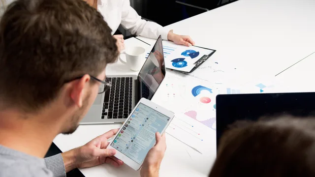 Modern team collaboration in office with laptops and tablets focusing on charts and communication. Kundesystemer: Sådan vælger du CRM til din virksomhed
