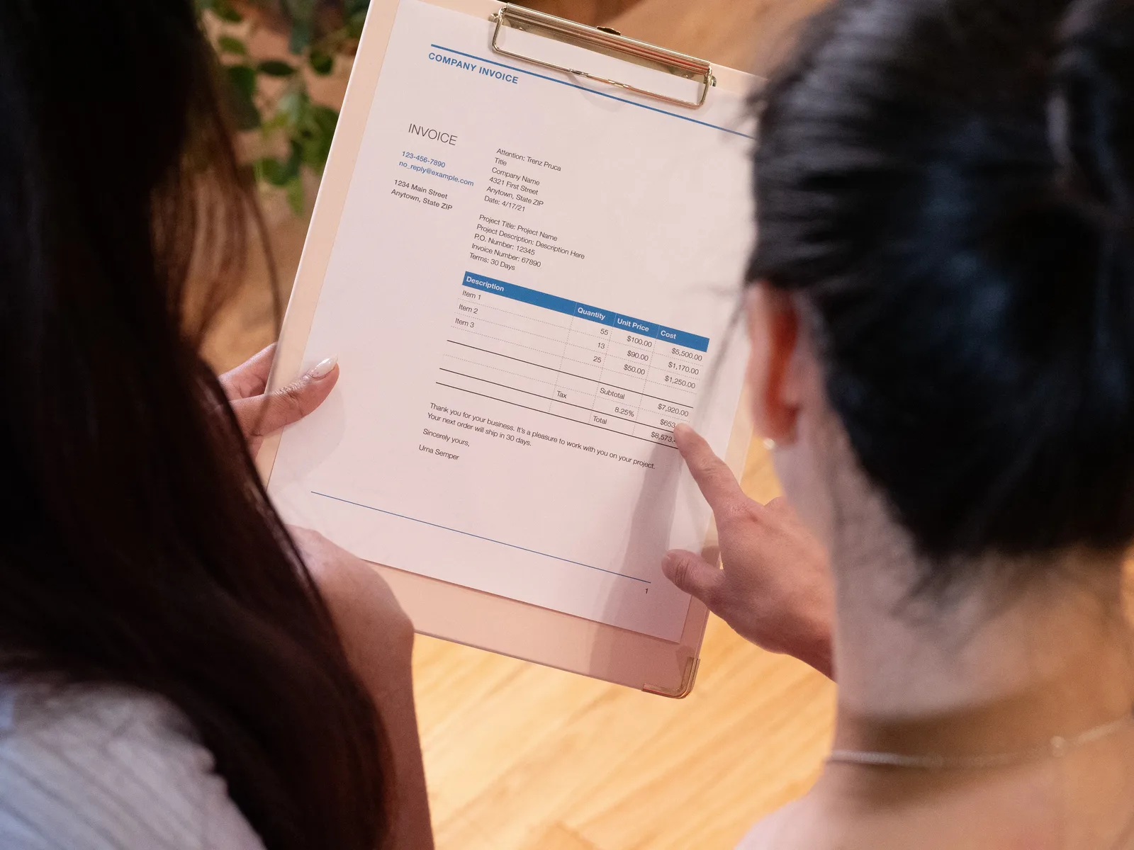 Two individuals reviewing an invoice together in a modern office setting.